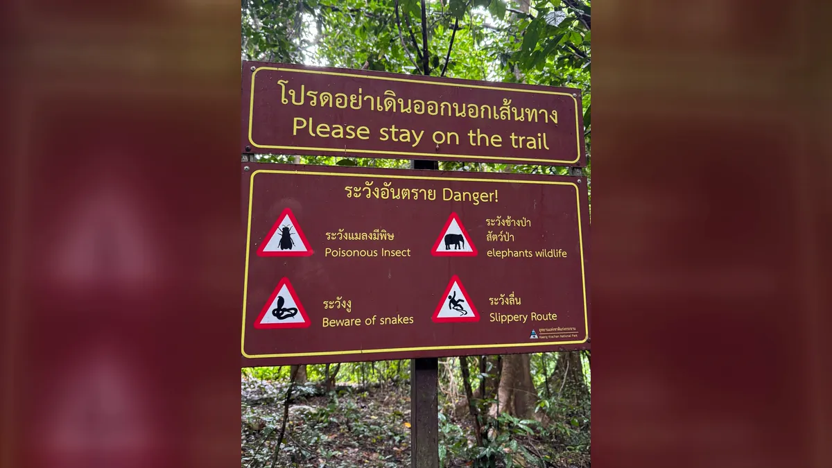 Sign in Kaeng Krachan National Park reading Please stay on the trail, with warnings about poisonous insects, snakes, elephants and slippery routes